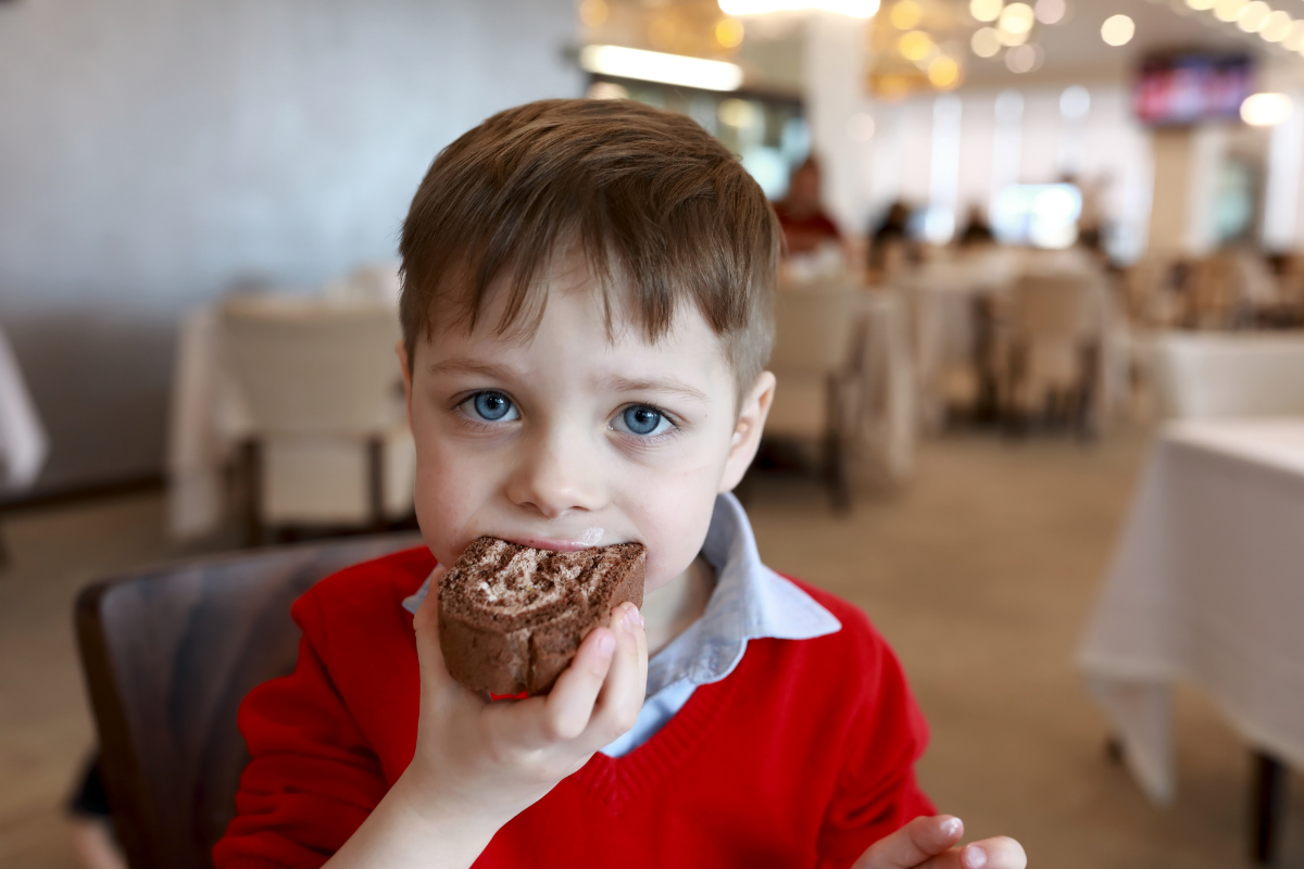 young child eating cake overeating and developing pediatric obesity