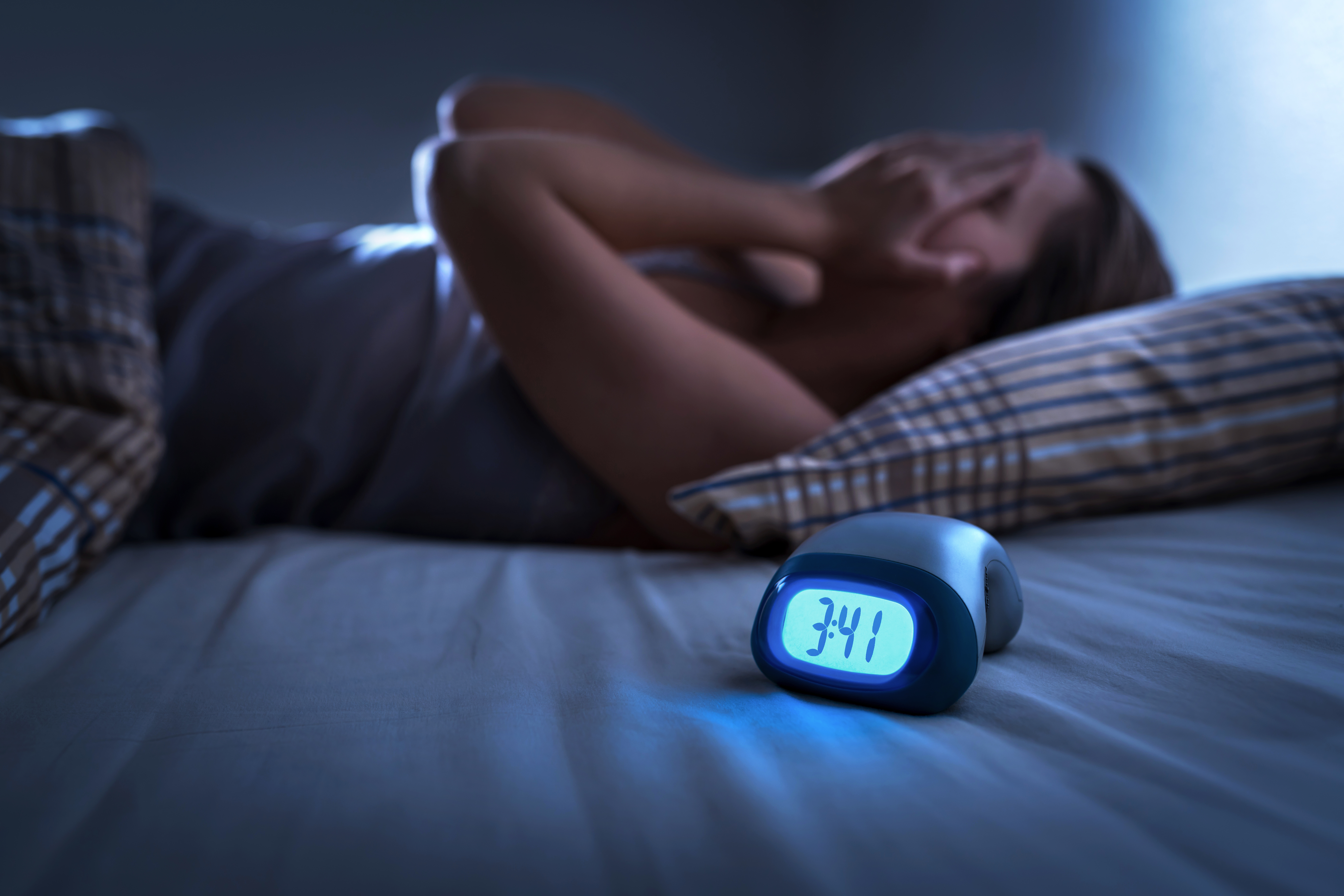 woman having trouble sleeping with a clock that says 3:41am