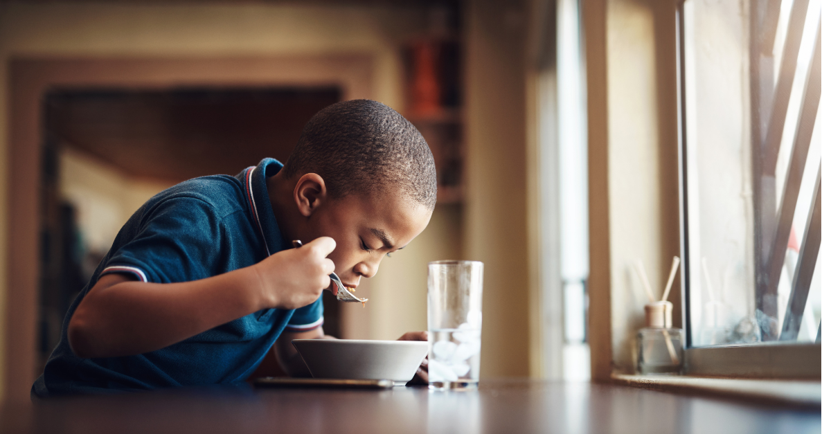 a child enjoying a bowl of cereal at a table.