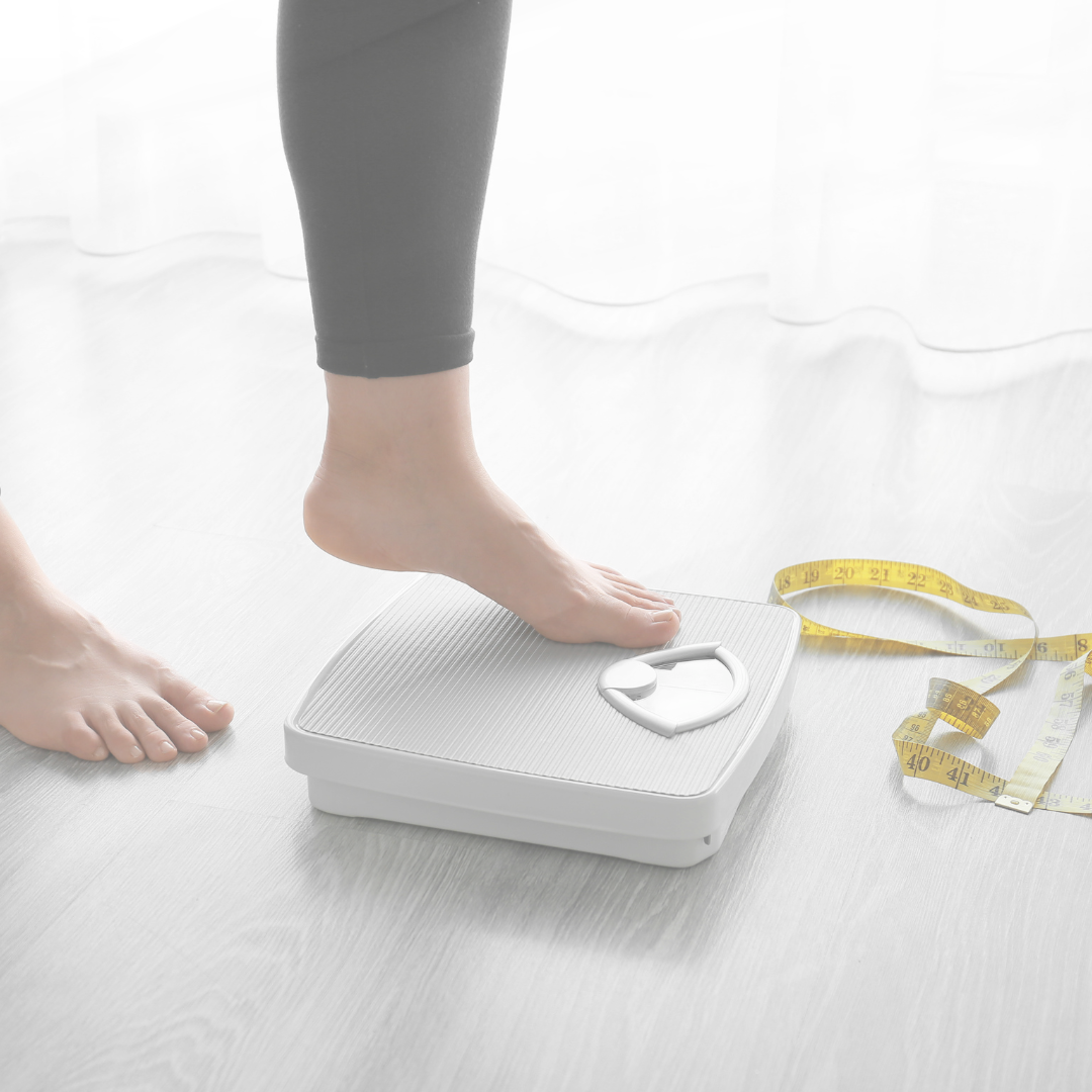foot stepping on a digital scale that shows BMI