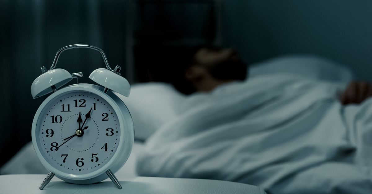 man sleeping in bed with an alarm clock in the frame