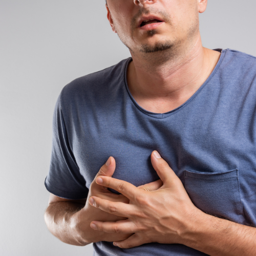 man clutching his chest because of heartburn