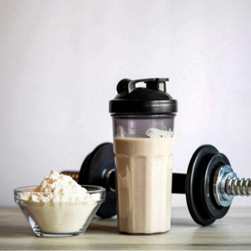 overhead view of pea protein powder, hemp seeds, matcha, almond milk, and leafy greens used in plant-based energy and protein drinks